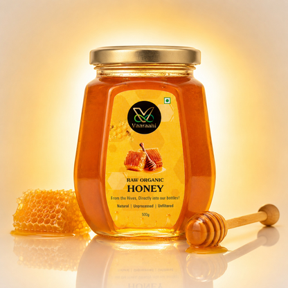Vaaraahi Raw Honey 500g jar with honeycomb and wooden honey dipper in warm golden lighting.